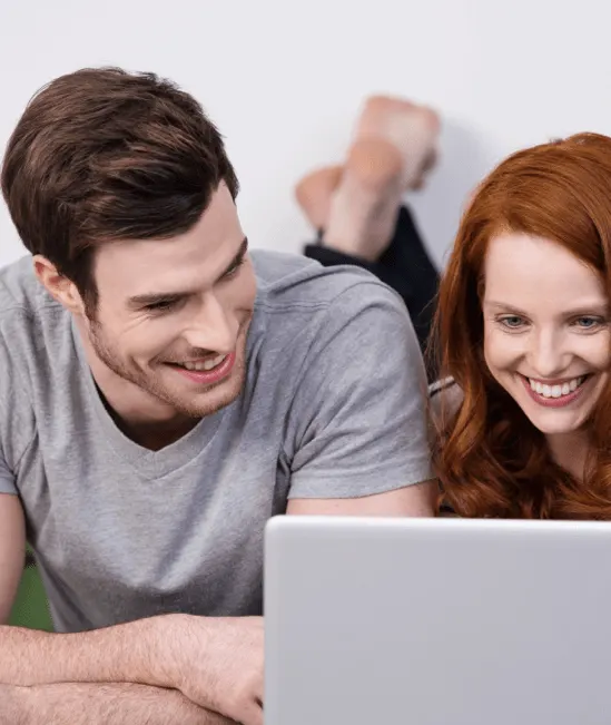 Happy couple looking into laptop | Carpetland USA Granite & Flooring